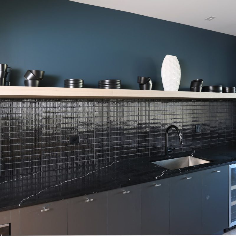 Sophisticated bar area with dark cabinetry, black marble countertops, and premium appliances at Station 250 luxury apartments Mundelein IL near Vernon Hills