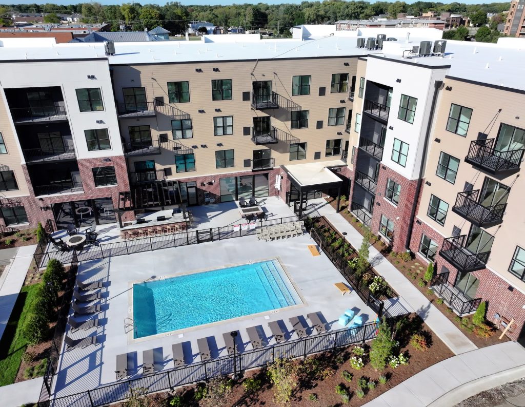 Outdoor swimming pool with lounge chairs and umbrellas at Station 250 apartments Mundelein IL