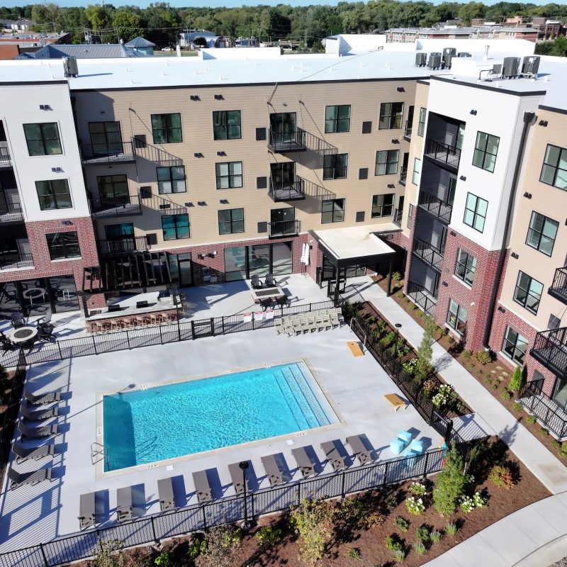 Outdoor swimming pool with lounge chairs and umbrellas at Station 250 apartments Mundelein IL