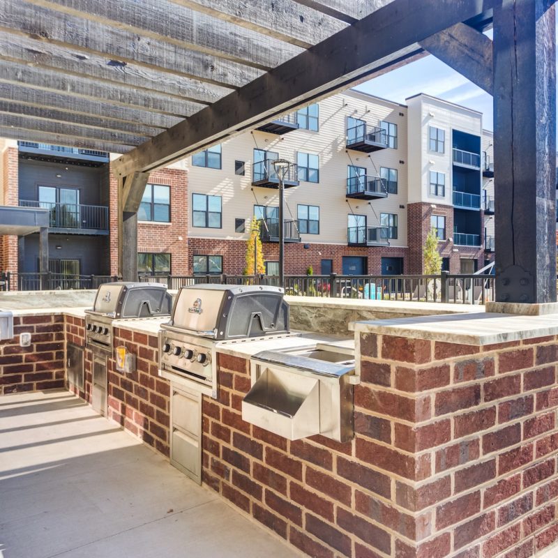Communal outdoor grilling station with multiple BBQ grills and pergola seating at Station 250 luxury apartments Mundelein IL near Vernon Hills