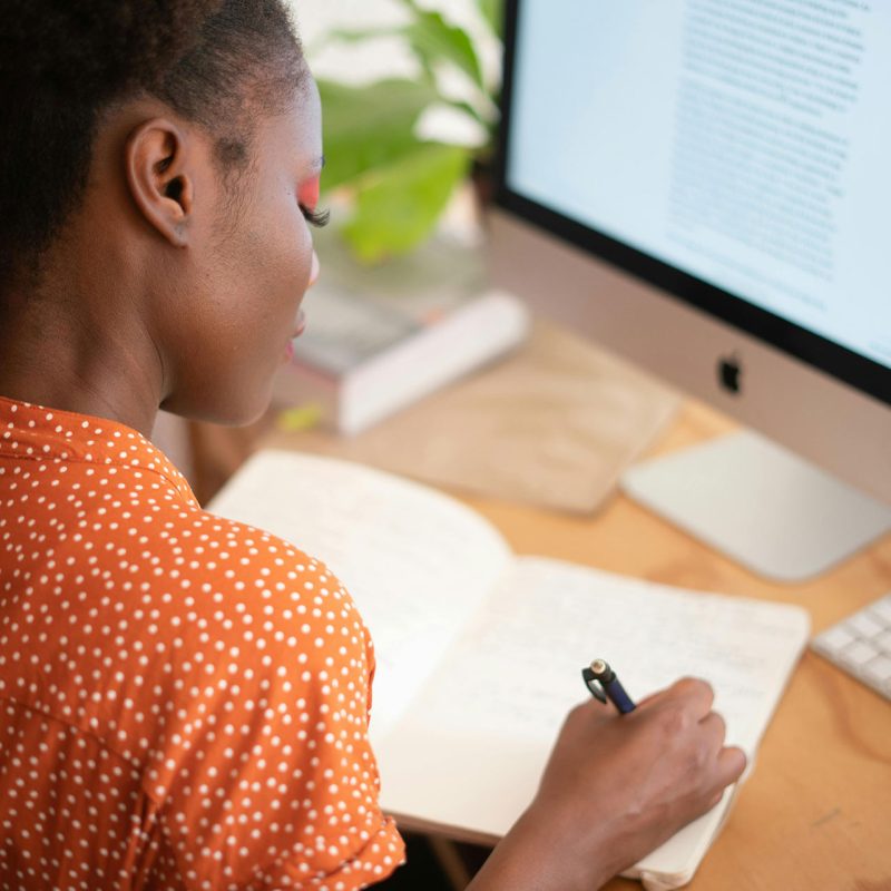 Woman writing in notebook at desk